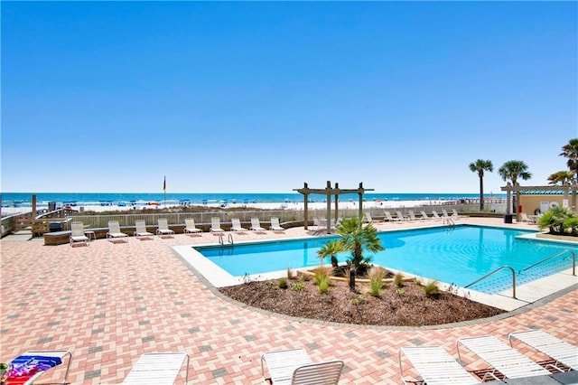 pool with a patio, fence, and a water view