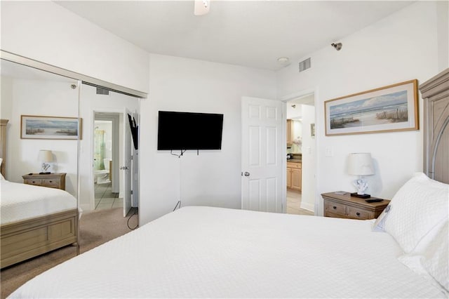 bedroom featuring visible vents, connected bathroom, baseboards, and light carpet