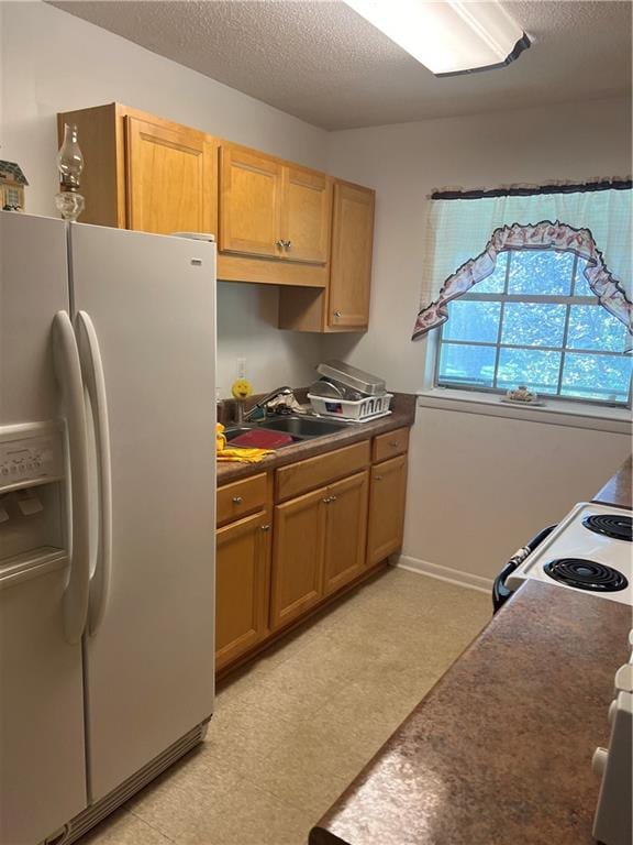 kitchen with white appliances, a textured ceiling, and sink