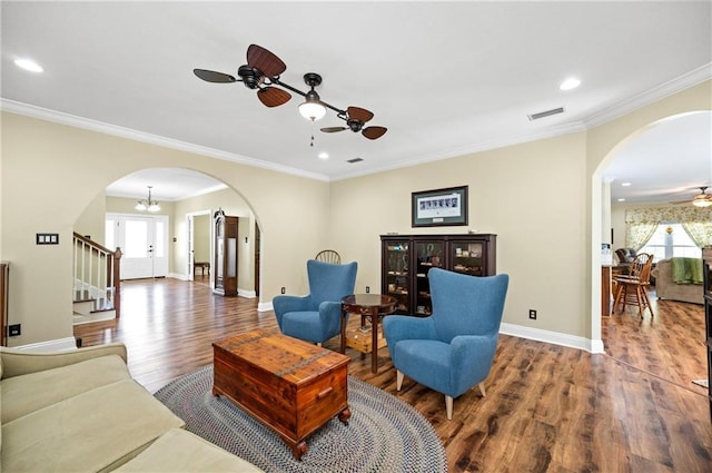 living room with ceiling fan with notable chandelier, dark hardwood / wood-style floors, and crown molding