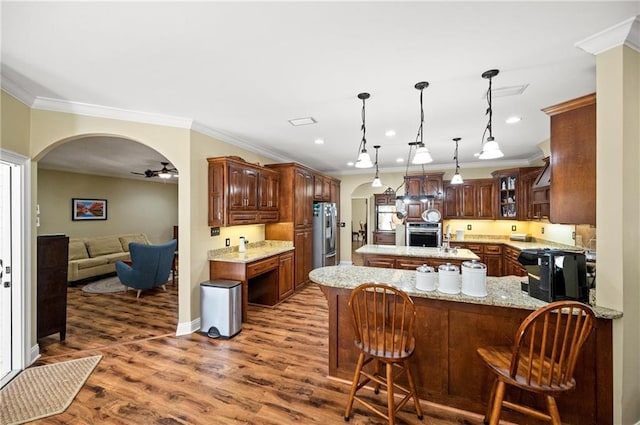 kitchen featuring stainless steel appliances, kitchen peninsula, ornamental molding, a kitchen breakfast bar, and dark hardwood / wood-style floors