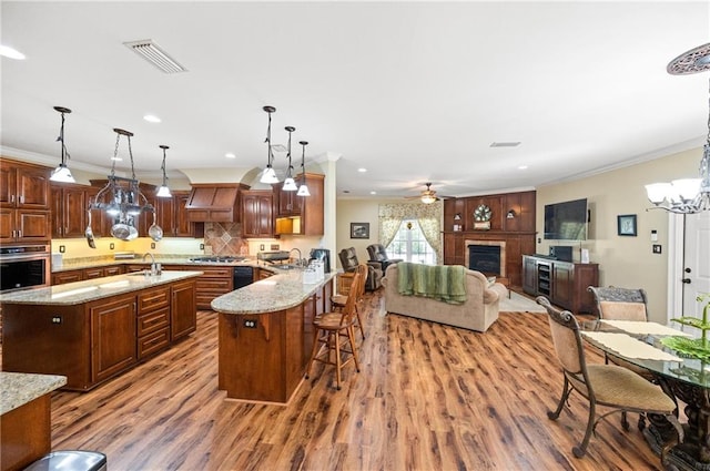 kitchen with stainless steel appliances, hanging light fixtures, hardwood / wood-style flooring, a breakfast bar area, and kitchen peninsula