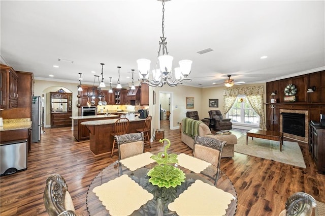 dining room featuring dark hardwood / wood-style flooring, crown molding, and ceiling fan with notable chandelier