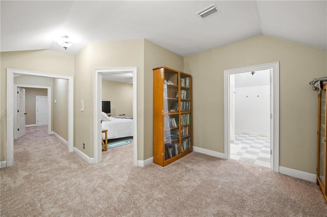 corridor with vaulted ceiling and light colored carpet