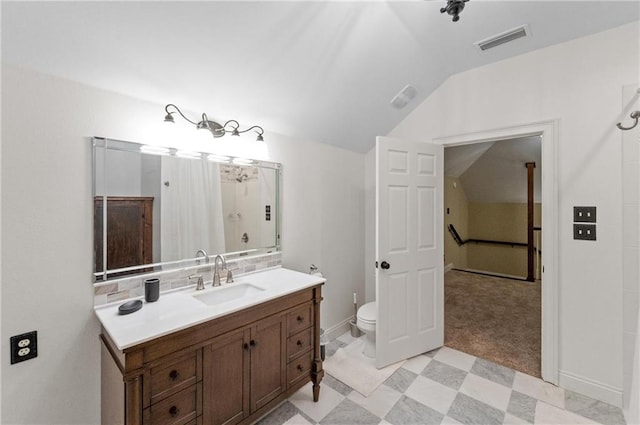 bathroom featuring toilet, vanity, and vaulted ceiling