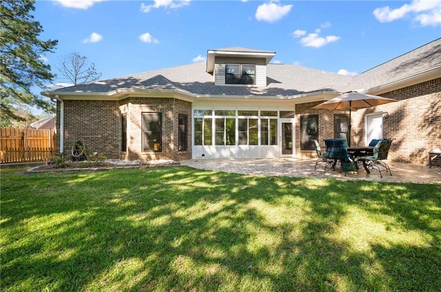 rear view of house with a lawn, a sunroom, and a patio