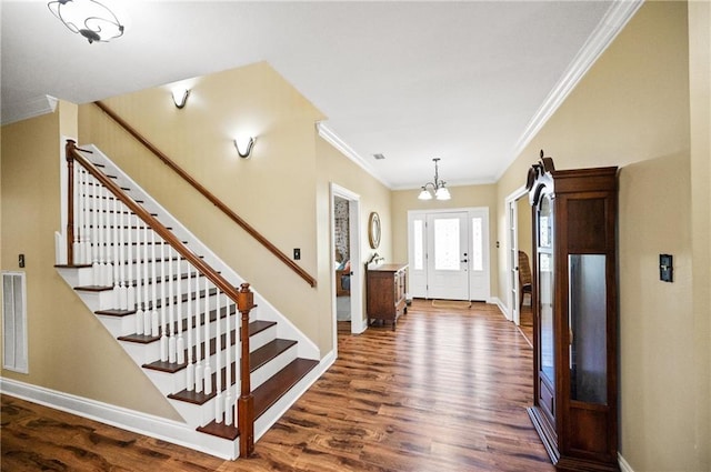 foyer featuring dark wood-type flooring, a notable chandelier, and ornamental molding