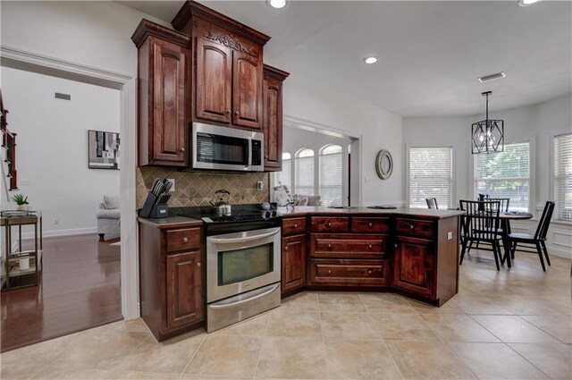 kitchen featuring a notable chandelier, light tile patterned floors, backsplash, hanging light fixtures, and stainless steel appliances