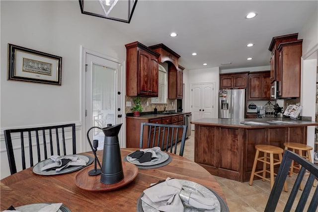 interior space with appliances with stainless steel finishes, tasteful backsplash, a breakfast bar, kitchen peninsula, and sink