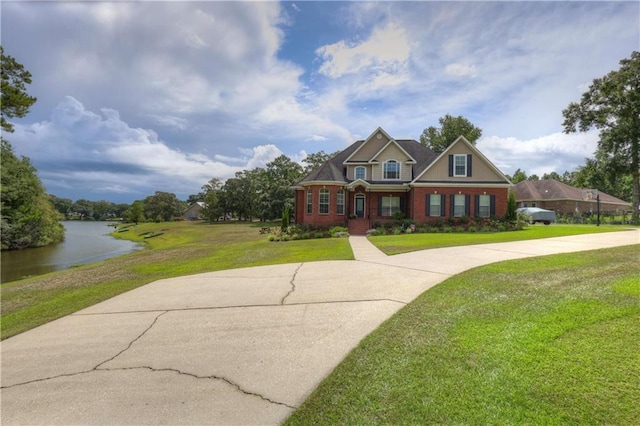 view of front facade featuring brick siding, driveway, a front lawn, and a water view