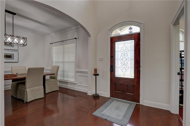 foyer entrance with baseboards, arched walkways, wood finished floors, and ornamental molding