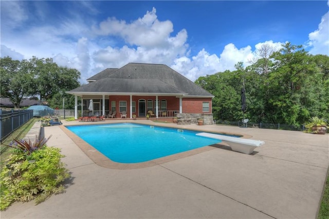 view of swimming pool featuring a diving board and a patio area