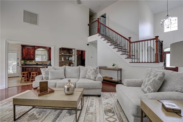 living room with high vaulted ceiling, light hardwood / wood-style flooring, and an inviting chandelier