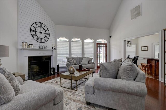 living room featuring a tiled fireplace, high vaulted ceiling, and hardwood / wood-style flooring