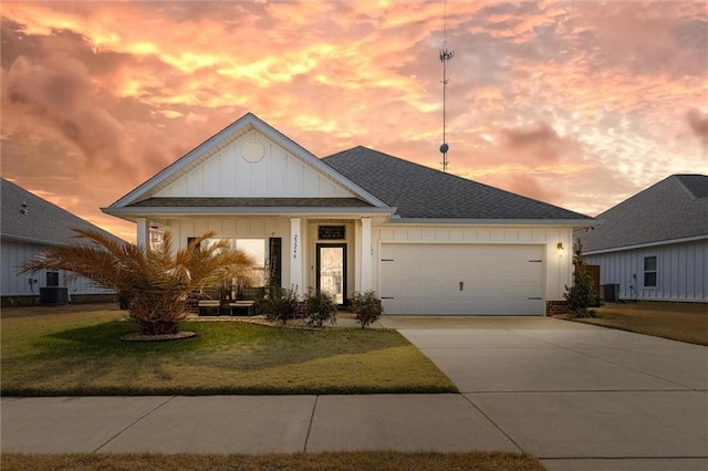 view of front facade with a garage, central AC unit, and a lawn