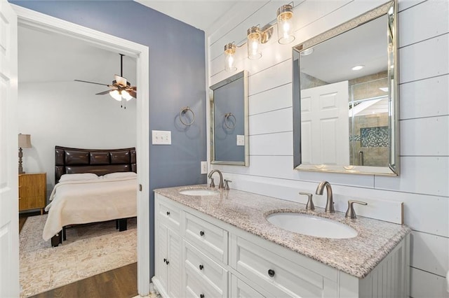 bathroom featuring ceiling fan, wood finished floors, a shower stall, and double vanity