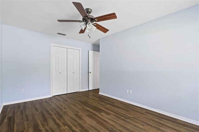 unfurnished bedroom with baseboards, dark wood-style flooring, and a closet