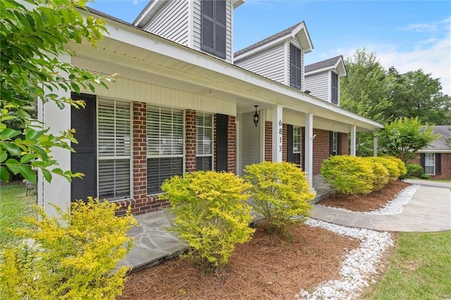 property entrance with brick siding and a porch