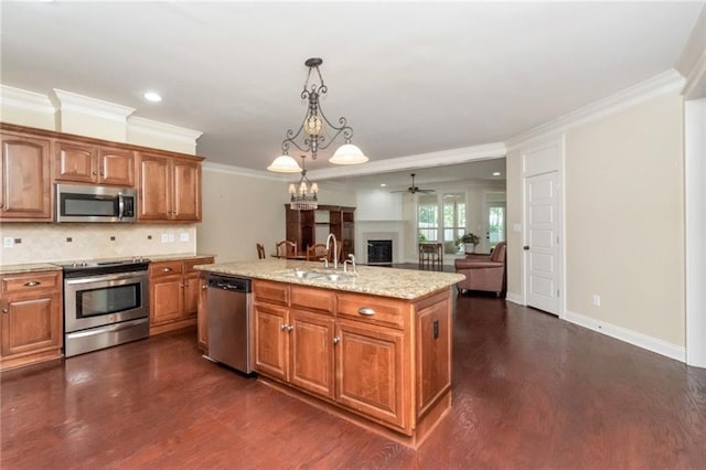 kitchen with a fireplace, appliances with stainless steel finishes, open floor plan, a kitchen island with sink, and a sink