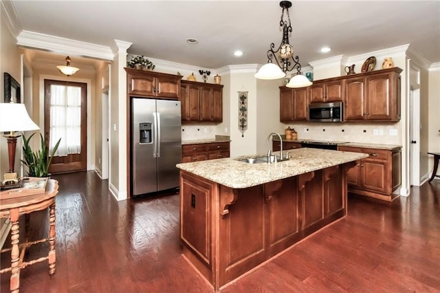 kitchen with a kitchen island with sink, a sink, appliances with stainless steel finishes, light stone countertops, and dark wood finished floors