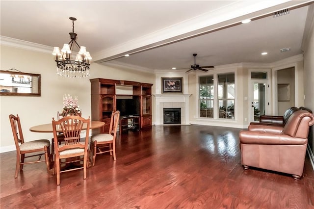 dining space with a fireplace, dark wood-type flooring, ceiling fan with notable chandelier, and ornamental molding