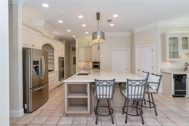 kitchen featuring a large island with sink, a sink, ornamental molding, light countertops, and stainless steel appliances