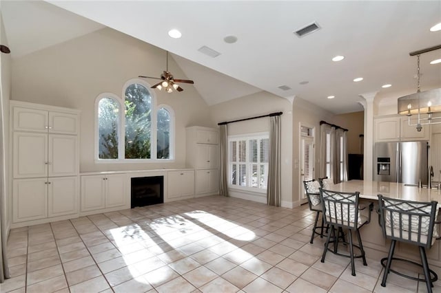 kitchen with a breakfast bar area, plenty of natural light, stainless steel fridge with ice dispenser, and visible vents