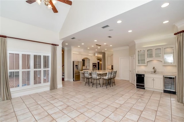 kitchen featuring visible vents, wine cooler, a kitchen bar, and stainless steel fridge with ice dispenser