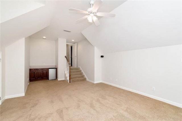 bonus room with baseboards, light colored carpet, stairs, vaulted ceiling, and a ceiling fan