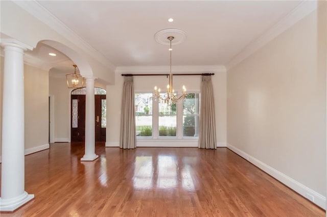 unfurnished dining area with decorative columns, baseboards, arched walkways, and ornamental molding