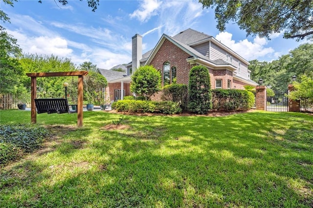 view of side of property with brick siding, a chimney, a lawn, and fence