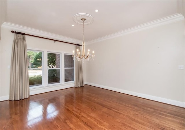 spare room featuring crown molding, wood finished floors, baseboards, and a chandelier