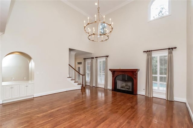 unfurnished living room with ornamental molding, wood finished floors, a fireplace, baseboards, and stairs