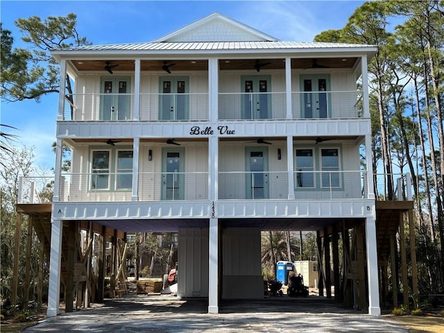 view of front facade with driveway, board and batten siding, a balcony, and a ceiling fan