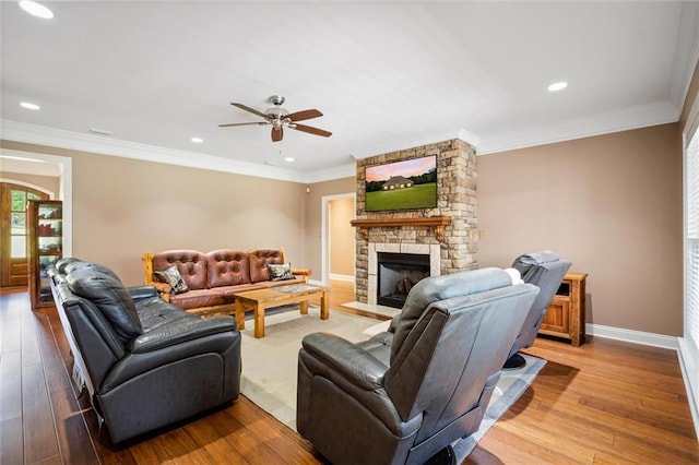 living room featuring light hardwood / wood-style floors, ornamental molding, and a stone fireplace