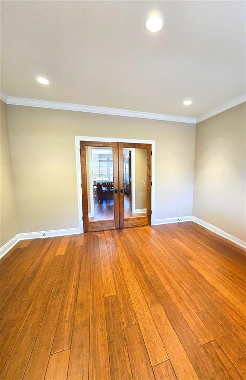 spare room featuring french doors, crown molding, and hardwood / wood-style floors