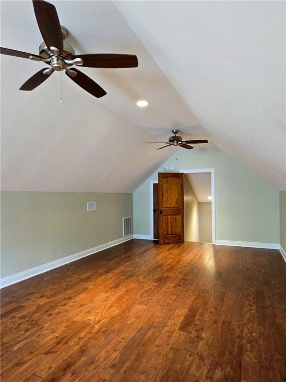 bonus room featuring lofted ceiling, dark hardwood / wood-style floors, and ceiling fan