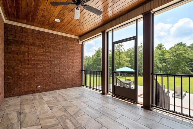 unfurnished sunroom featuring ceiling fan, wooden ceiling, and a wealth of natural light