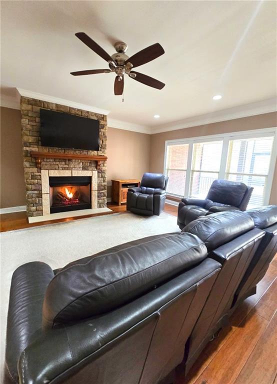 living room featuring a fireplace, hardwood / wood-style floors, ceiling fan, and ornamental molding