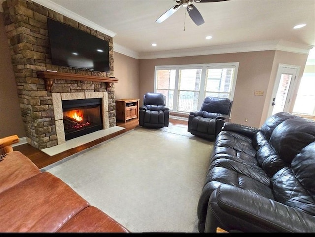 living room featuring hardwood / wood-style flooring, ceiling fan, crown molding, and a fireplace