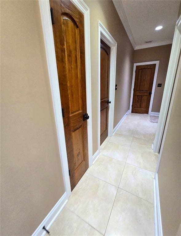 corridor featuring light tile patterned floors and ornamental molding