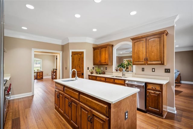 kitchen with sink, light wood-type flooring, appliances with stainless steel finishes, and an island with sink