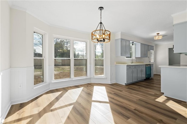 kitchen with dark hardwood / wood-style floors, a notable chandelier, ornamental molding, stainless steel dishwasher, and sink