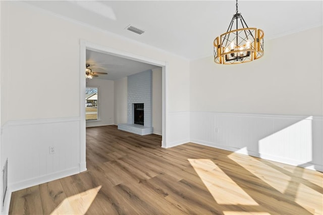 dining space featuring hardwood / wood-style flooring, ceiling fan with notable chandelier, radiator heating unit, and a fireplace