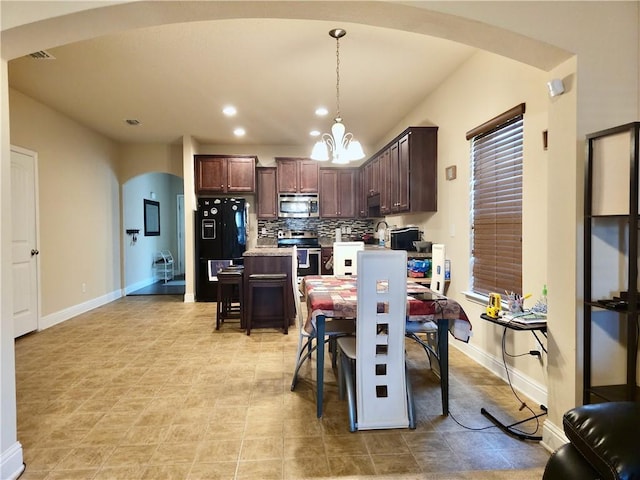 dining area with arched walkways, baseboards, a notable chandelier, and recessed lighting