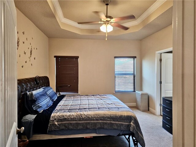 bedroom featuring ceiling fan, crown molding, a raised ceiling, and light carpet