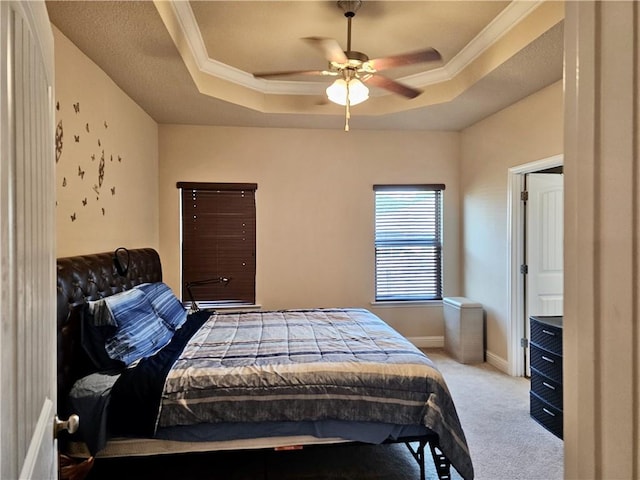 bedroom featuring a tray ceiling, light carpet, ornamental molding, and ceiling fan