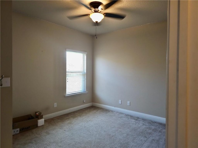 carpeted spare room with a ceiling fan and baseboards