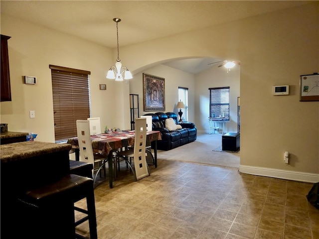 dining space with ceiling fan with notable chandelier and lofted ceiling