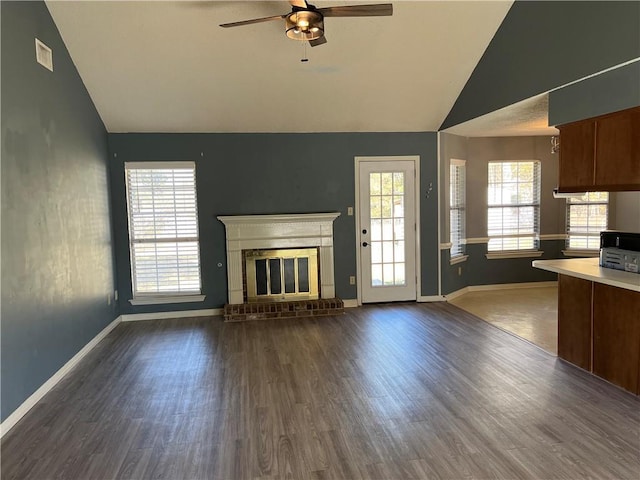 unfurnished living room with a fireplace, vaulted ceiling, and plenty of natural light